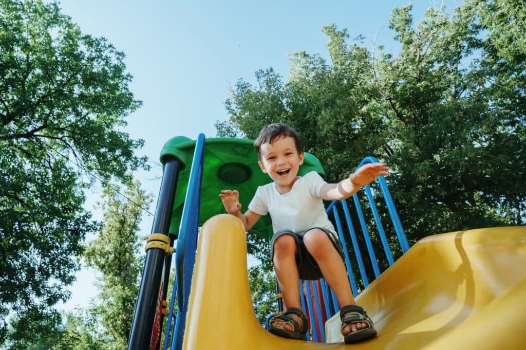 Happy,Preschooler,Boy,Playing,On,A,Slide,On,The,Playground