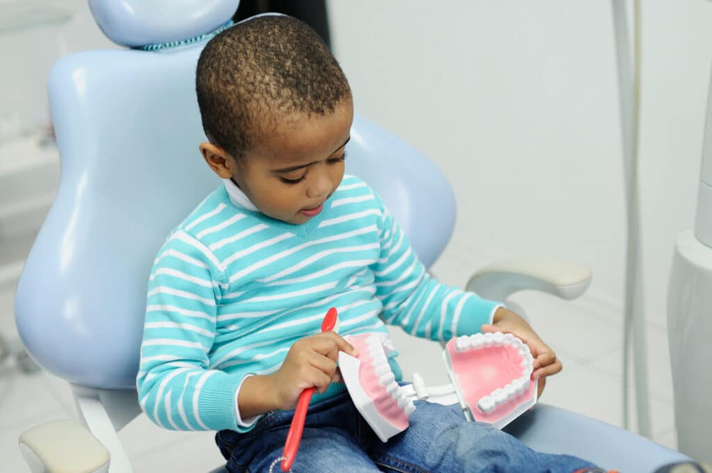 Little,Boy,In,A,Striped,Sweater,,Sitting,In,The,Dental